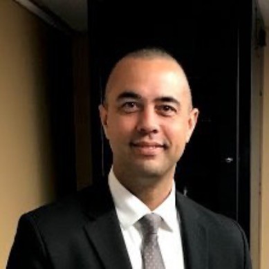 Headshot of a man smiling, wearing a suit