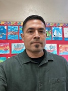 carlos campa An Educator posing in front of a wall covered in art made by students