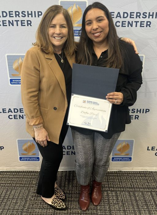 Two women posing, holding up a certificate