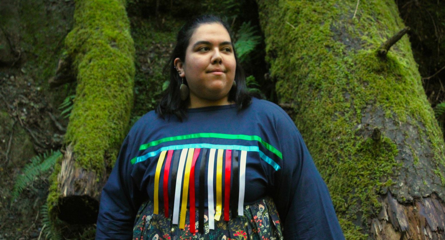 Lindsey - Medium Headshot of a woman in colorful native dress in front of mossy background