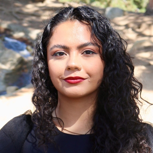 Headshot of a woman with black curly hair and bright red lipstick