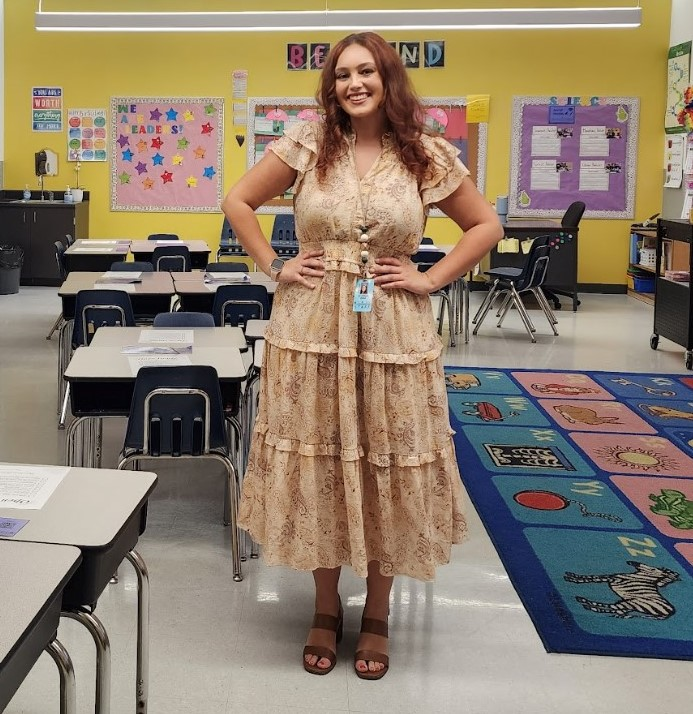 Teacher wearing a flowery dress, smiling and posing