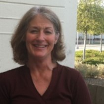 Headshot of a person standing in front of a building, smiling