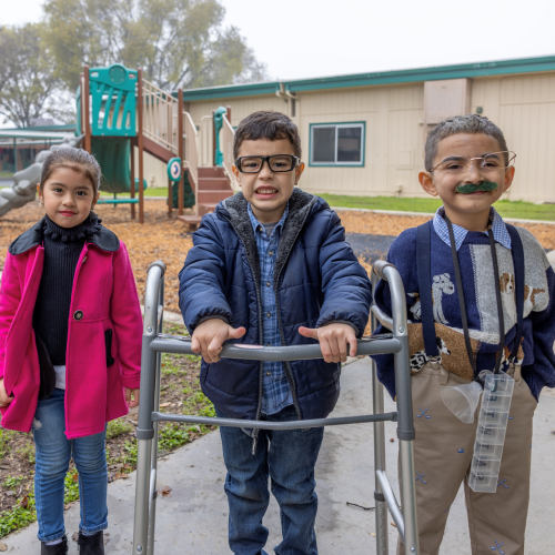 Three students standing in front of a play structure