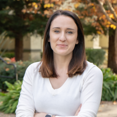 Headshot of a woman with arms crossed, smiling