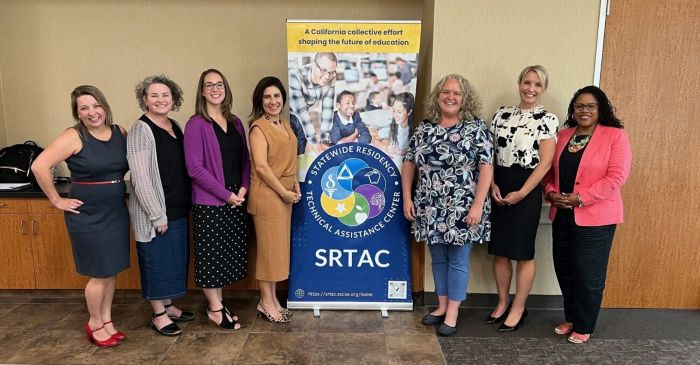 Group of smiling people posing in front of a SRTAC sign.